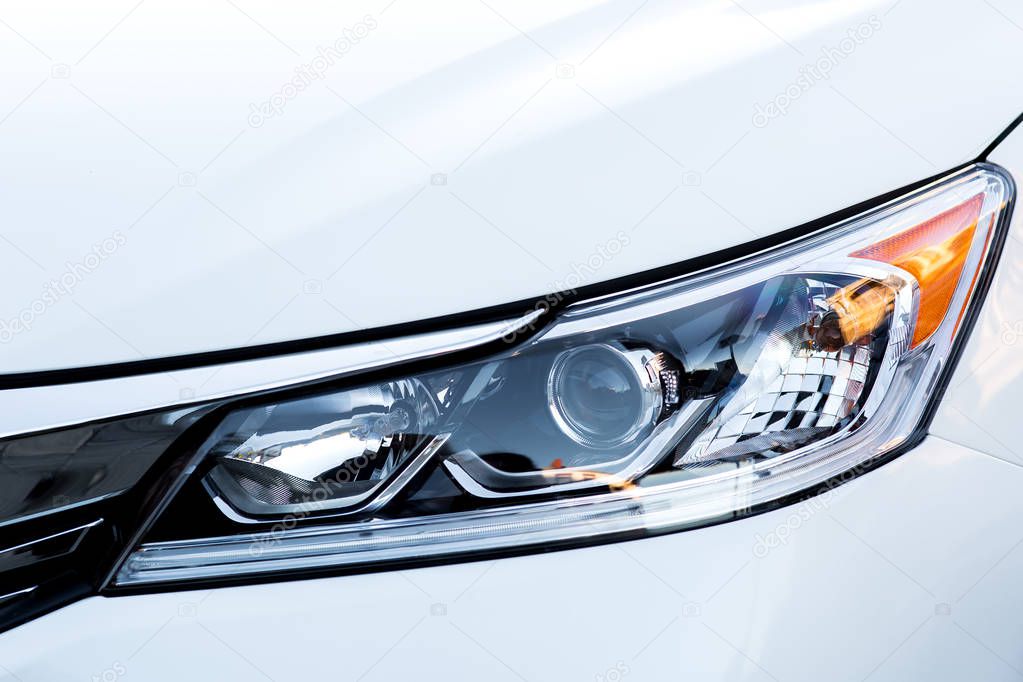 car headlight close up, xenon light with lens on a white car.