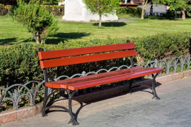 kahverengi panoları ve demir siyah bacaklar arka planı yeşil bitki örtüsü Şehir parkındaki ahşap Bank.