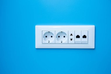 a socket on a light blue wall, a multiple outlet with an internet connection, two European type and one American type outlet. clipart