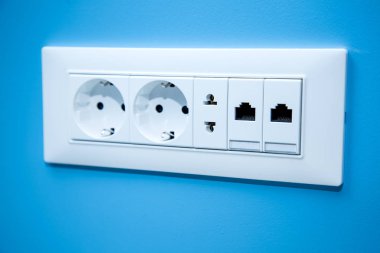 Elektrik Fişleri ve elektrik için elektrik prizi güç lamak için Avrupa ve Amerikan stanlart bir dizi soket ve Internet kablo yakın çekim mavi duvardaki bağlanmak.
