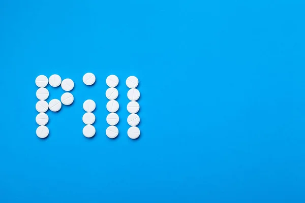 The inscription Pills of white pills on a blue background top view with copy space for text.