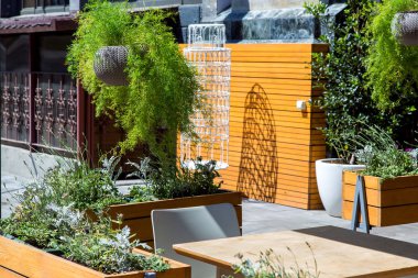 Bitki saksıları Çiçeklik asılı ve kaldırımda yüklü yaz kafe sitesinde içinde.