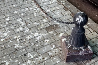 Siyah baba kuş pisliği içinde kirli bir yaya kaldırımda bir zincir ile kaldırım kuş pisliğine tabaka..