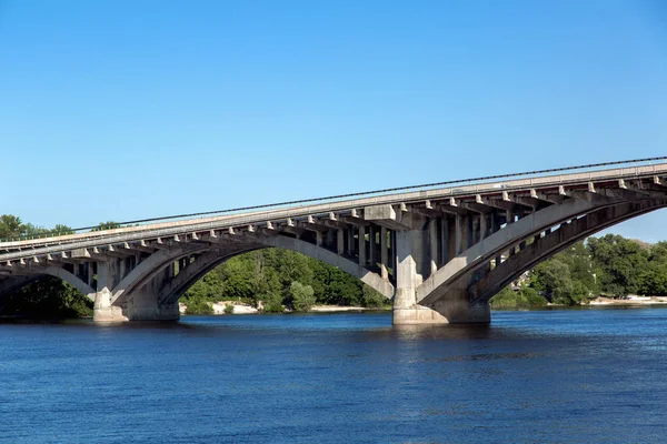 Suyu ve yeşil ağaçları arka planı kemerli monolitik beton yapı köprüdür gölet.