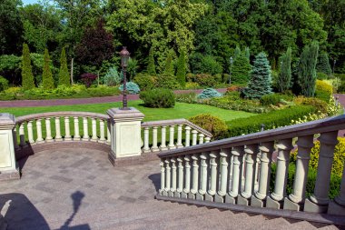 taş merdiven korkuluk korkuluklar ve fenerler üzerinde bir park bir manzara ile aşağı inen ve bitkiler Bahçe kaideleri ile.