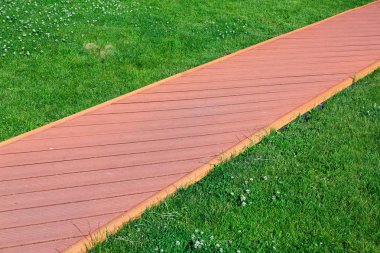 yol bir kaldırıma yakın çekim yeşil bir çim bir geçit ile ahşap plakalar şeklinde kırmızı taş döşeme.