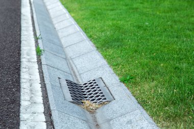 gutter of a stormwater drainage system in perspective on the side of an road with markings and lawn. clipart