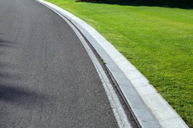 Yağmursuyu hendek su ve yol boyunca yeşil çim glade ile yolun kenarında olan asfalt yol.