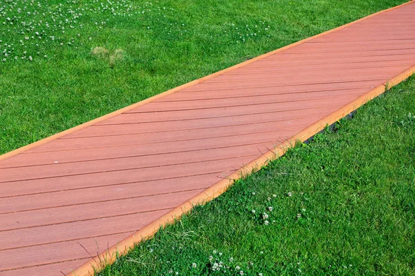 红色石砖的路径 以木板的形式与路边 与绿色草坪的人行道特写镜头 — 图库照片