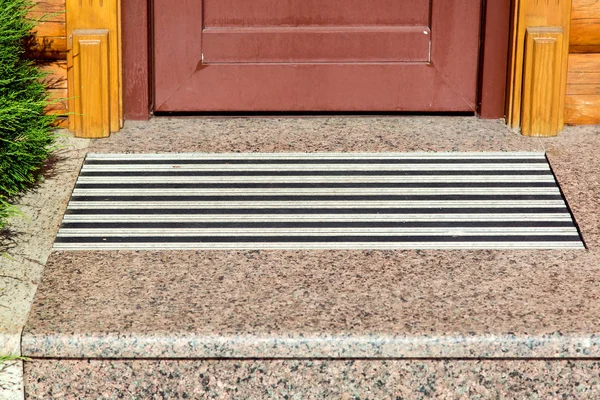 entrance threshold with a marble step and a rubber foot mat close-up front view.