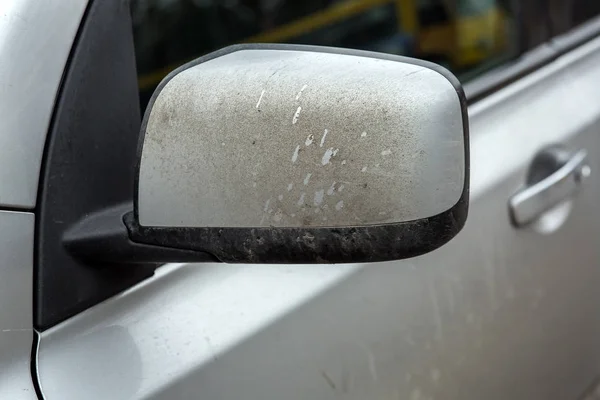 rearview mirror of a dirty car of gray color, closeup of a car part in the dirt.