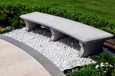 taş gri tezgah boxwood çalılar ve bitkiler ile yeşil bir çim ile bir bahçede beyaz taş çakıl ile serpiştirilmiş, oturma ve güneşli bir yaz bir mermer kiremit geçit yakınında dinlenme için bir yer yakın.