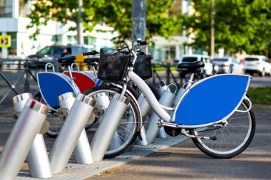 trafik sıkışıklığı ile yolun arka planda bir şehir parkında bisiklet kiralama, mavi reklam alanı ile kiralık bisiklet gri.