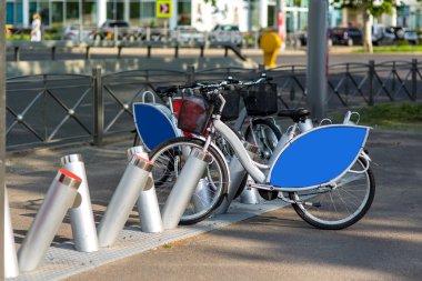 yolun arka planda bir şehir parkında bisiklet kiralama, mavi reklam alanı ile kiralık bisiklet gri.