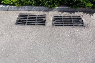 güneşli bir günde yol yüzeyinden yakın çekim su ortadan kaldırmak için fırtına drenaj kanalizasyon ızgaraile asfalt yol.