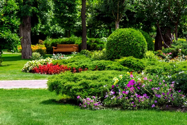 ağaçların altında gölgede yolları ve ahşap banklar ile bir eğlence parkı bitkiler ile çiçekli.