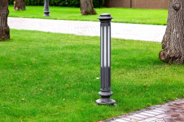 Yağmurdan sonra bir yaz günü yeşil alanlar arasında patika ile parkın yeşil çim yüklü Demir zemin bahçe fener, kimse.