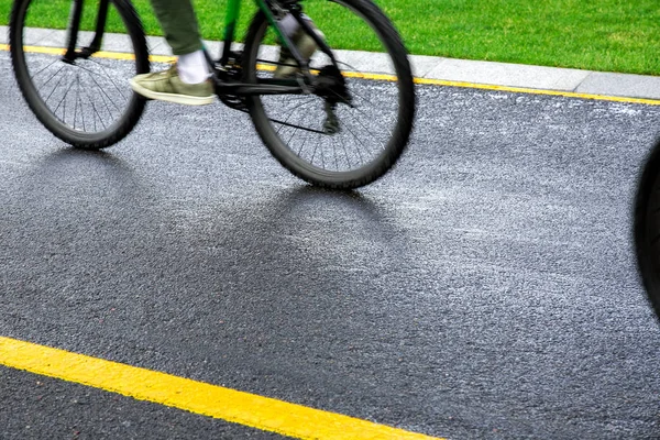 asphalt bike path wet after rain with yellow markings with a passing black bike blurred in motion, sports background on a bicycle theme close up.
