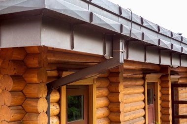 Kerestelerden yapılmış ahşap bir çatı üzerindeki kahverengi plastik drenaj borusu..