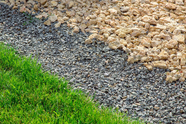 Landscaping yard with rows of stones scattered with green lawn, close up decor detail.