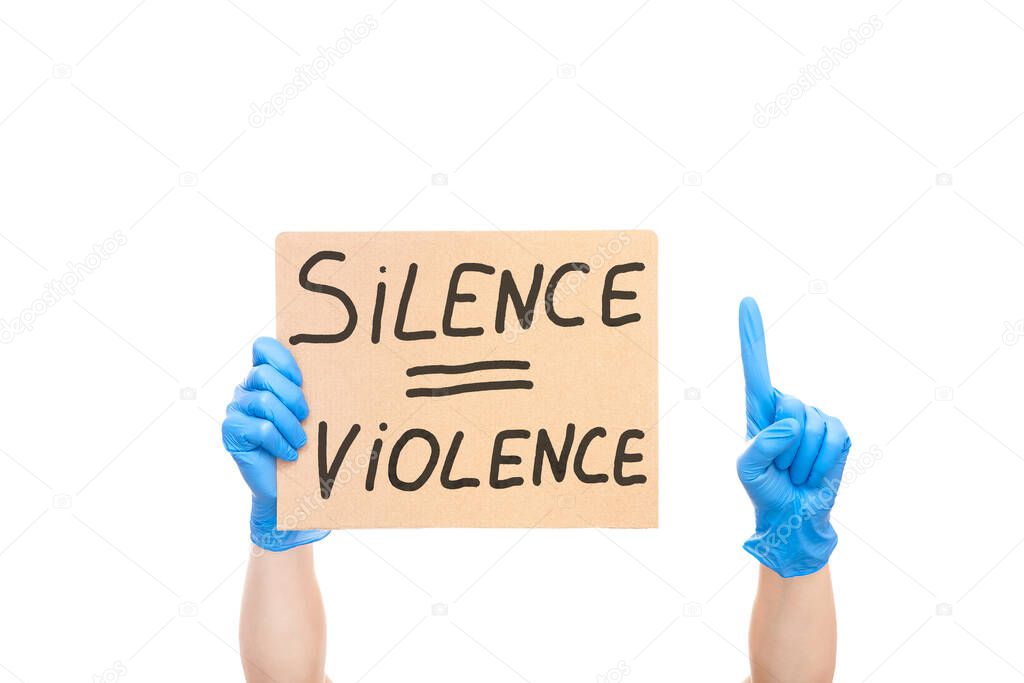 protest shows index finger up and  hand on glove holding a cardboard poster with the message text silence is violence isolated on white background, concept on the theme of protest at police brutality.