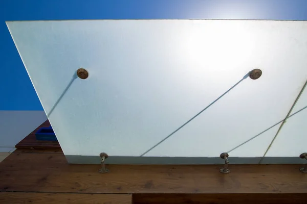 建筑立面入口处的玻璃垫护目镜 用金属紧固件固定在木制墙体上 背景为蓝天和太阳的棕色 是现代建筑的缩影 — 图库照片
