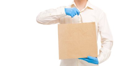 Teslimatçı, beyaz arka planda izole edilmiş pandemik sosyal uzaklık karantinası sırasında BM etiketli eko dostane paketinde güvenli yiyecek taşıması için steril kurye eldivenleri getirdi..