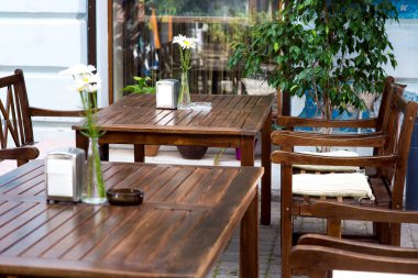 Açık havada dinlenmek için açık masaları olan açık bir kafe. Binanın ön cephesinde bir pencere ve bitkilerle dolu saksılar..