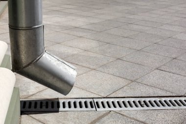 Sokak mühendisliği yapısı, arka planında kanalizasyon oluğu olan, kare karolardan kopyalanmış granit kaldırım, yan görünümü olan bir boru..