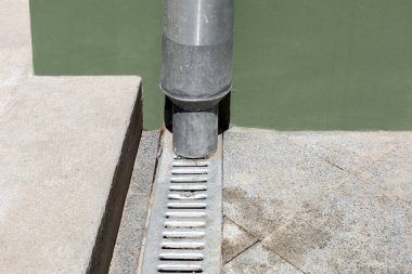 Mühendislik yapısı, yeşil cephe binasının ön cephesinde gri taş zemininin drenaj ızgarası ve çimento eşiği ile birlikte altyapıyı kapatıyor. Kopya alanı olan kentsel altyapı, hiç kimse.