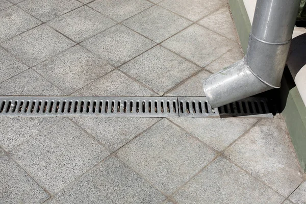 Mühendislik şehrinin gelişimi kanalizasyon ızgarası ile arka plandaki gri taş granit kaldırımın kare karolarından, yan görünüşten hiç kimseye yakın değil..