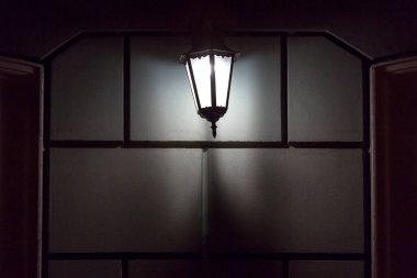 Siyah demir retro fener binanın ön cephesinde asılı cam gece şehrin mimarisini aydınlatan, yakın plan parlak ön görüş, hiç kimse.