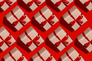 Kırmızı arka planda yalıtılmış kırmızı kurdele ile Kraft kağıdında desen hediye kutusu, şenlik arka planında üst görünüm.