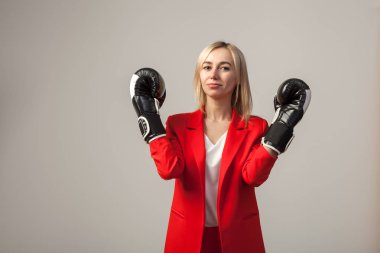 Bir ceket ve beyaz bluz ayakta beyaz izole arka planda boks eldivenli bir poz ile kırmızı sıkı elbiseli Genç güzel beyaz sarışın kız