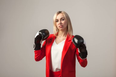 Bir ceket ve beyaz bluz ayakta beyaz izole arka planda boks eldivenli bir poz ile kırmızı sıkı elbiseli Genç güzel beyaz sarışın kız