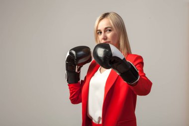 Bir ceket ve beyaz bluz ayakta beyaz izole arka planda boks eldivenli bir poz ile kırmızı sıkı elbiseli Genç güzel beyaz sarışın kız