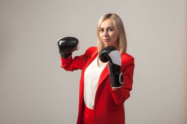 Bir ceket ve beyaz bluz ayakta beyaz izole arka planda boks eldivenli bir poz ile kırmızı sıkı elbiseli Genç güzel beyaz sarışın kız