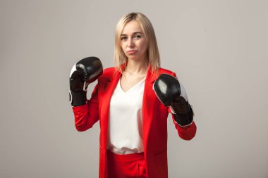 Bir ceket ve beyaz bluz ayakta beyaz izole arka planda boks eldivenli bir poz ile kırmızı sıkı elbiseli Genç güzel beyaz sarışın kız