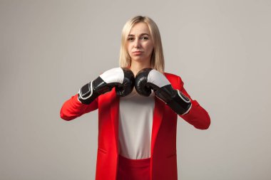 Bir ceket ve beyaz bluz ayakta beyaz izole arka planda boks eldivenli bir poz ile kırmızı sıkı elbiseli Genç güzel beyaz sarışın kız