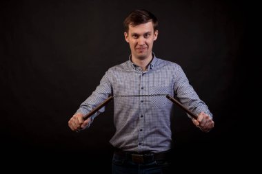 Esmer adam ekose gömlekli bir nunchuck izole siyah arka plan üzerine onun elinde tutan