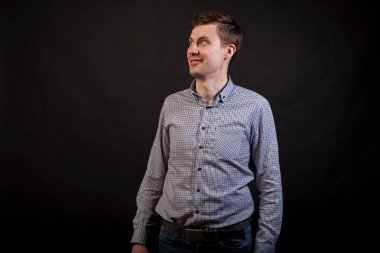 Koyu saçlı beyaz adam ararken ve gülümseme ekose gömlek ve siyah Yalıtılmış zemin kot