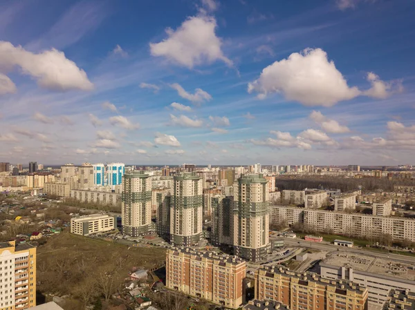 Three buildings in the city colored in green and grey and blue sky with clouds. Different buildings from small to large