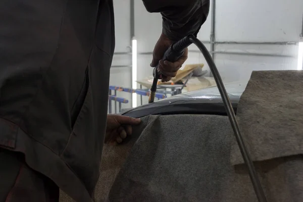 Experienced man performs work on body repair car with a welding machine. Repair of the roof of the vehicle.