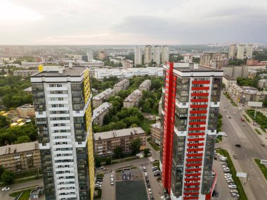 Kırmızı ve sarı renk ile otomobil ve yeşil ağaçlar ve çalılar ile bahçede çocuk oyun Park yeri küçük binalar arasında iki uzun boylu gökdelenler ile manzara havadan görünümü