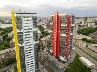 Kırmızı ve sarı renk ile otomobil ve yeşil ağaçlar ve çalılar ile bahçede çocuk oyun Park yeri küçük binalar arasında iki uzun boylu gökdelenler ile manzara havadan görünümü