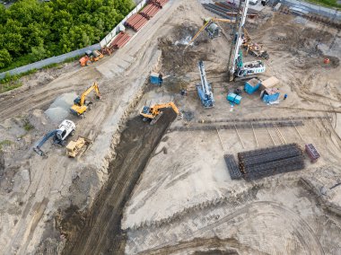 İnşaat alanında bir sondaj teçhizat, ekskavatör ve üç kamyon toprak ulaşım için yüklenmesini beklemek ile zemin hazırlanması ve inşaat ilk aşamada hava üstten görünüm