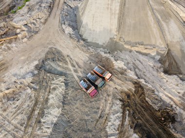 Üç İpucu kamyon kum ve toprak kum yüzeyi ve düzensiz zemin arasında hedefe köy yolunda bir inşaat sitesinde yükleme bekleyen yanyana duran hava üstten görünüm