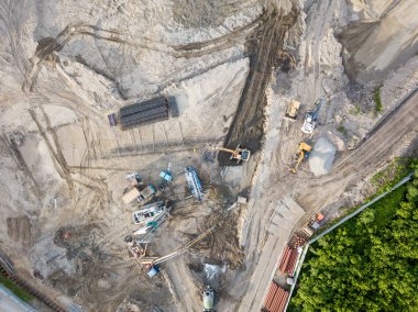 İnşaat alanında bir sondaj teçhizat, ekskavatör ve üç kamyon toprak ulaşım için yüklenmesini beklemek ile zemin hazırlanması ve inşaat ilk aşamada üstten görünüm