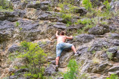Climber jeans gömlek içinde genç adam ve çıplak gövde buzlu Altay Dağları ekipman ve sigorta olmadan en tepeye tırmanıyor