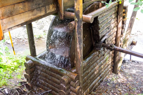 An old water mill in the mountains of the Altai producing electricity, through which water flows forming a waterfall spraying drops